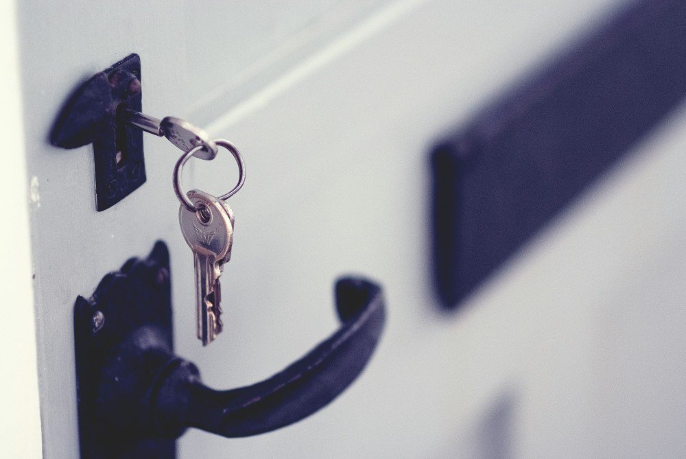 Clé engagée dans la serrure d’une porte blanche à poignée noire